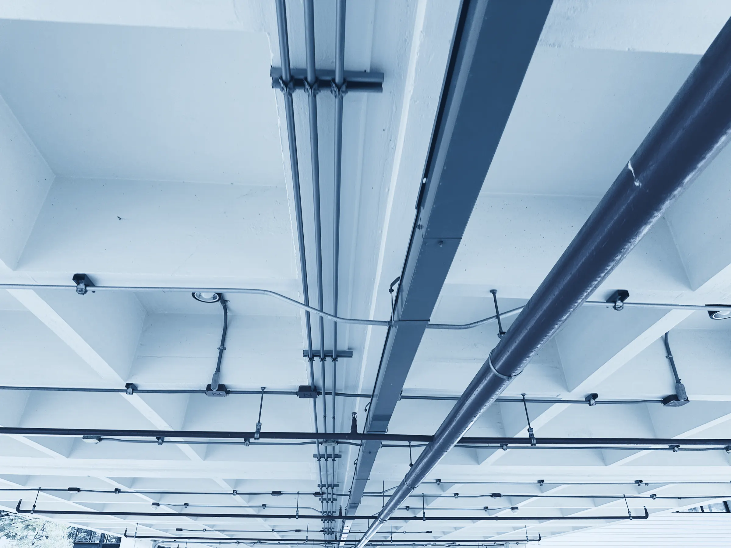 Sprinkler- und Kabeltrassen an einer Betondecke
